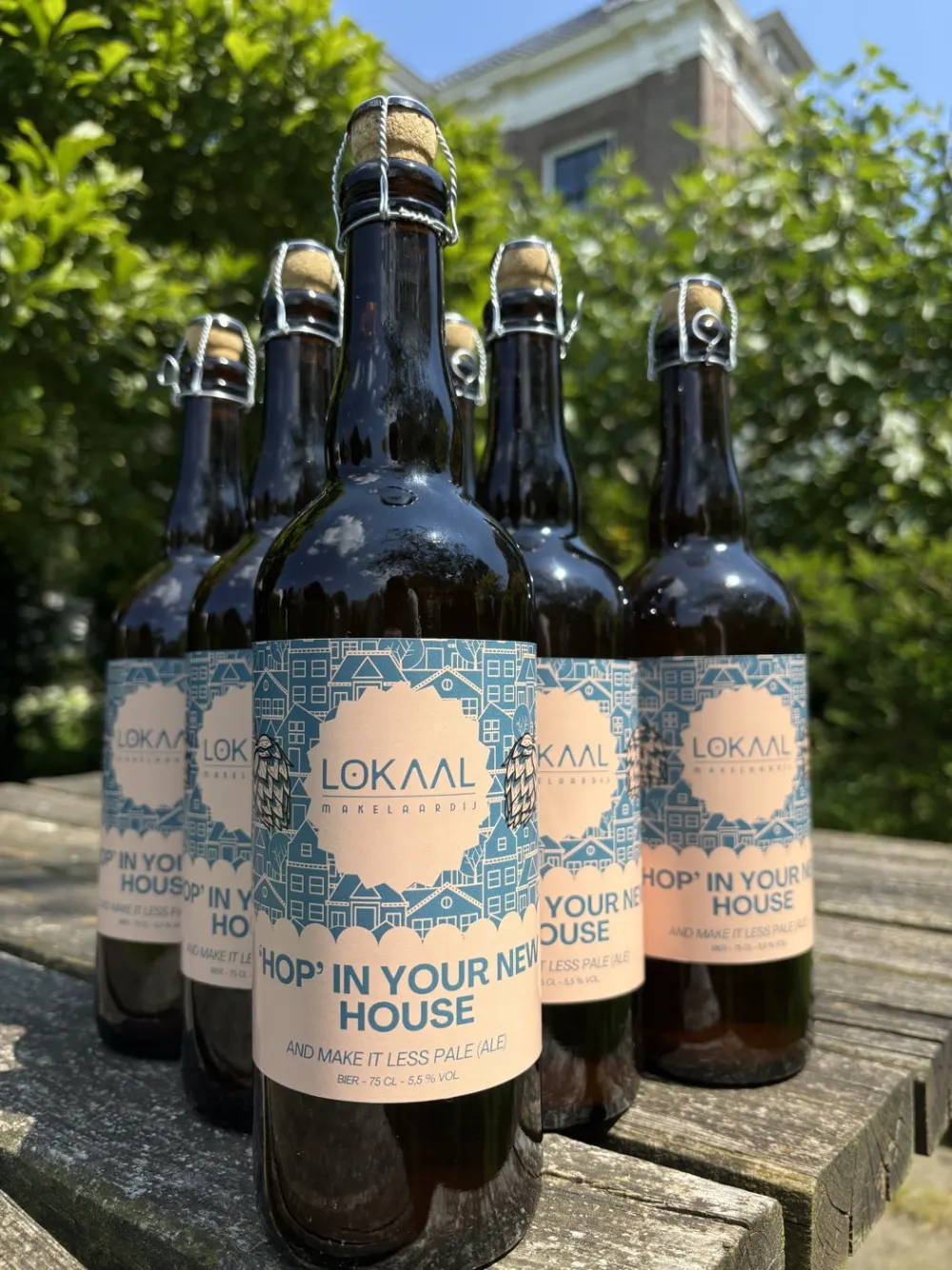 Flessen bier met het etiket van Lokaal Makelaardij: Hop' in your new house